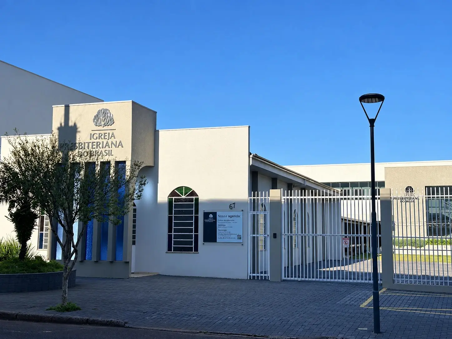 Fachada do templo da IPPB na Av. Brasil, 67, em dia de céu azul, com o letreiro Igreja Presbiteriana do Brasil e a sarça