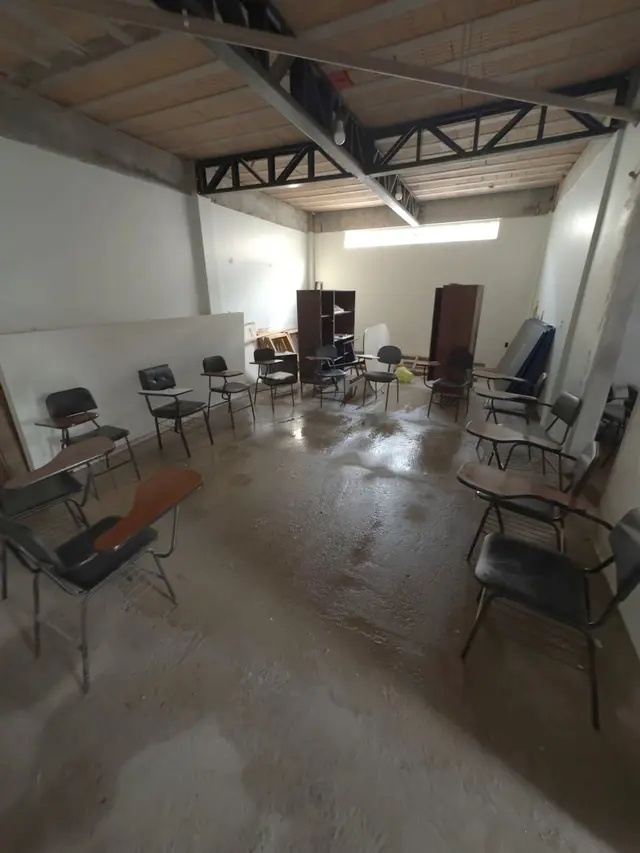 Sala em obra, com estrutura do teto aparente e cadeiras amontoadas