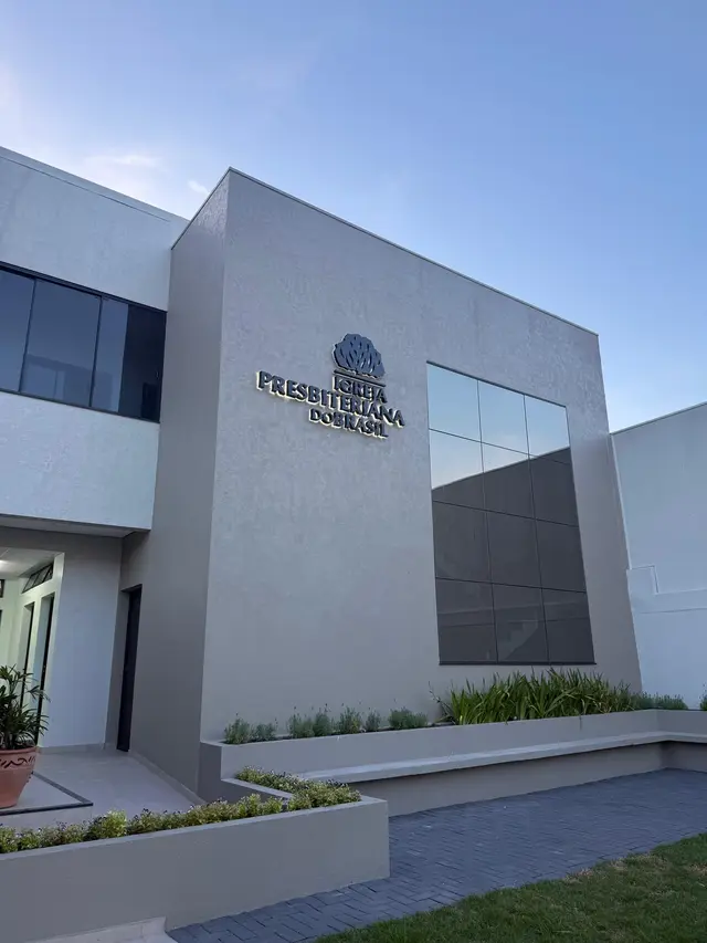 Prédio da igreja de dia, com paredes cinza, janela de vidro e o letreiro Igreja Presbiteriana do Brasil