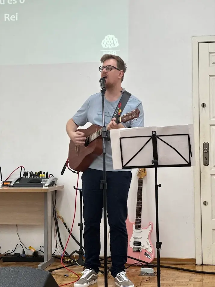 Músico do Ministério de Louvor cantando e tocando violão diante do telão da IPPB