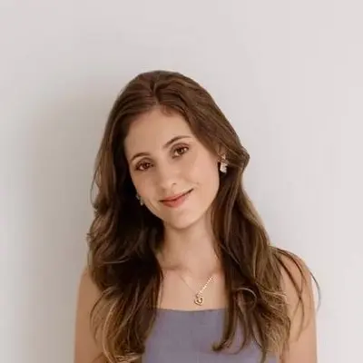 Retrato da Evangelista Milena sorrindo, diante de uma parede clara